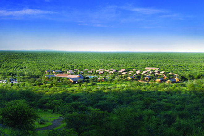 Aerial view of Damara Mopane Lodge, an oasis within the dry landscape of Damaraland of Namibia, temporarily lush green due to the summer rains